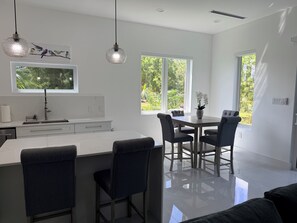 A modern kitchen with a central island, two pendant lights, and a dining area with a table and chairs. - Enjoyable 2-bedroom condo with AC in charming Savannah (Savannah)
