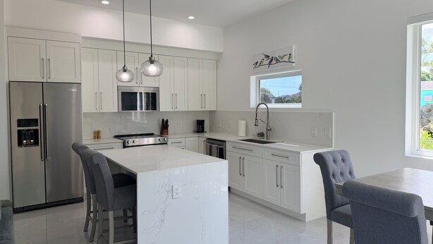 A modern kitchen with white cabinetry, stainless steel appliances, pendant lighting, and a large island. - #1 Enjoyable 2-bedroom condo with AC in charming Savannah (Savannah)