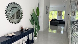A modern living room with a glass partition, a decorative mirror, a console table with 'LOVE' letters, and a large green plant. - #1 Enjoyable 2-bedroom condo with AC in charming Savannah (Savannah)