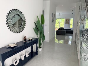 A modern living room with a glass partition, a decorative mirror, a console table with 'LOVE' letters, and a large green plant. - Enjoyable 2-bedroom condo with AC in charming Savannah (Savannah)