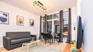 Ett modernt vardagsrum med en soffa, ett soffbord, ett matbord, stolar och en tv.