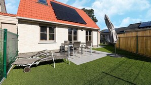 A house with a red roof, solar panels, a patio with chairs, and a fenced yard. - Holiday Home in Koksijde Near Sandy Beaches (Koksijde)