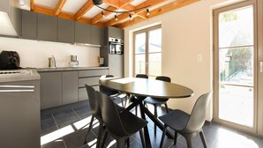 A modern kitchen with grey cabinets, a round dining table, and black chairs. - Holiday Home in Koksijde Near Sandy Beaches (Koksijde)