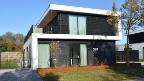 A modern two-story building with a balcony, a number '301' on the facade, and a small garden area in front. - Luxury 10p Villa on the Water Near Harderwijk (Zeewolde)