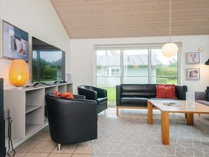 A modern living room with a sofa, chairs, a coffee table, and a TV. - 4 Star Holiday Home in Norre Nebel (Norre Nebel)