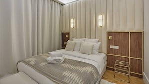 Ett modernt hotellrum med en stor säng, en garderob i trä och två väggmonterade lampor.