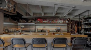 A bar area with a stainless steel counter, bar stools, and a variety of bottles on shelves. - NOK Amazing Apartment in Chapinero (Bogotá)