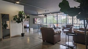 Ein geräumiges Zimmer mit großen Fenstern, einem Sofa, einem Couchtisch und einem Blumentopf.