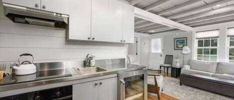 A modern kitchen with stainless steel appliances, a built-in oven, and a dining area with a sofa and table.