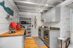 Une cuisine compacte avec des meubles blancs, un plan de travail en bois et un petit îlot central.