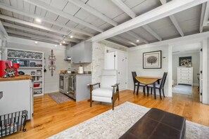 A spacious living area with a kitchen, dining table, and a white chair.