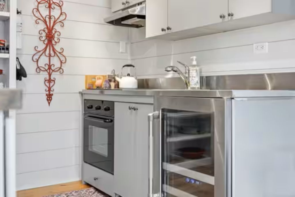 Une cuisine moderne avec des meubles blancs, un réfrigérateur en acier inoxydable et un four.