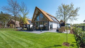 Een modern huis met een ruime glazen patio, een schuin dak en een verzorgd gazon.