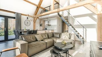 Een modern interieur met een houten plafond, een trap, een keuken en een zithoek met een bank en stoelen.