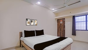 A bedroom with a bed, ceiling fan, artwork, window, and door. - Collection O Iskcon Aurangabad (Chhatrapati Sambhajinagar)