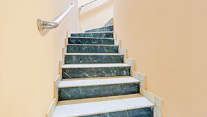 Una escalera con escalones de mármol y barandilla metálica.