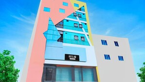 Un hotel de varios pisos con un llamativo letrero que dice 'HOTEL', amplias ventanas y un diseño arquitectónico moderno.