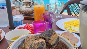 A table with breakfast items, including bread, eggs, and juice, near a pool. - Villa Aronora Private Pool & BBQ (Haddada)