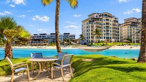 A resort with a pool, palm trees, and a beach. - Luxury Oceanfront Apartment - Playa Escondida 503 (Portobelo)