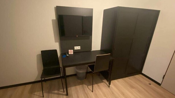 A small, compact room with a desk, two chairs, a trash bin, and a wardrobe. - 2 Person Holiday Park Home in Bendorf (Bendorf)