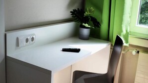 A small workspace with a desk, a chair, a potted plant, and a window with green curtains. - 2 Person Holiday Park Home in Bendorf (Bendorf)