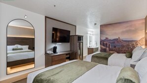 Habitación de hotel con dos camas, un escritorio, televisión y un mural grande en la pared.