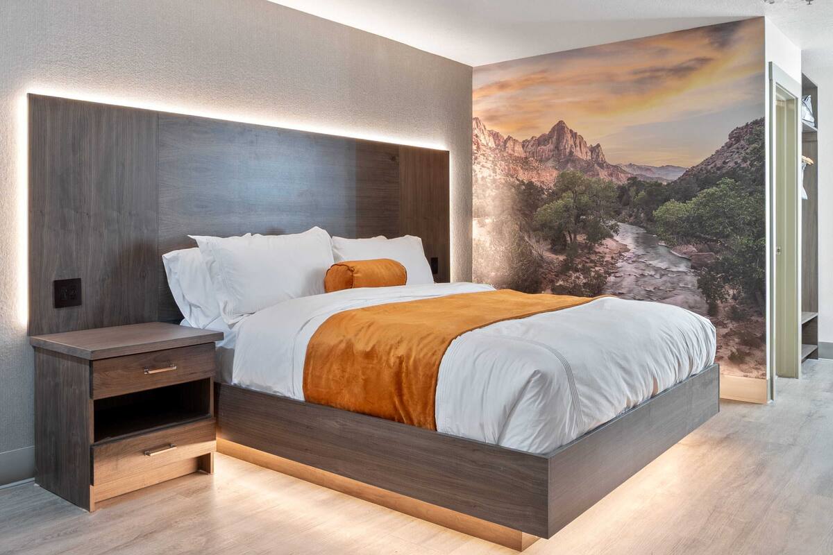A modern bedroom with a bed, nightstands, and a large wall mural.