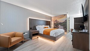 Un dormitorio moderno con cama, mesitas de noche, sofá, escritorio y televisor.