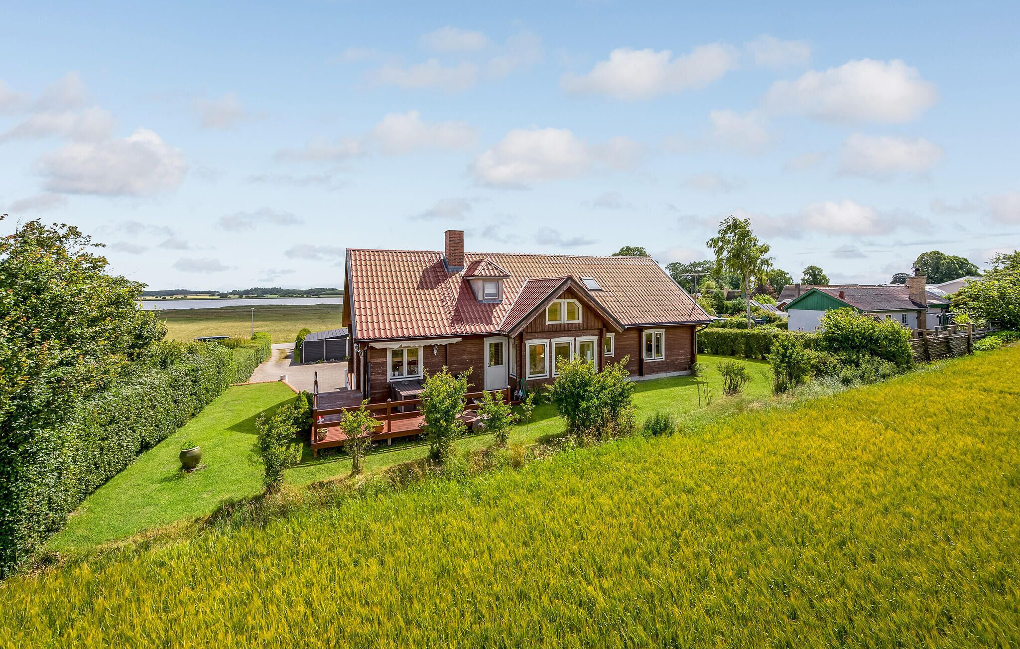 A two-story house with a red-tiled roof, a chimney, and a deck with outdoor furniture.