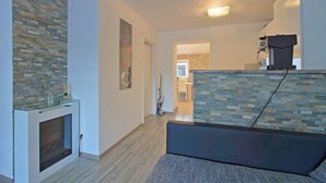 Ein modernes Wohnzimmer mit Kamin, einer Wand aus Stein und einer Sitzecke.