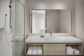 A modern bathroom with a shower, a sink, and a mirror. - AC Hotel Lenexa City Center (Lenexa)
