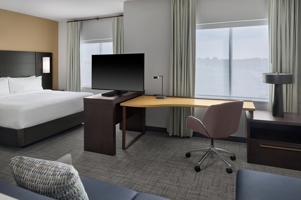 A hotel room with a bed, desk, chair, and a television.
