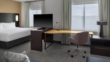 A hotel room with a bed, desk, chair, and a television.