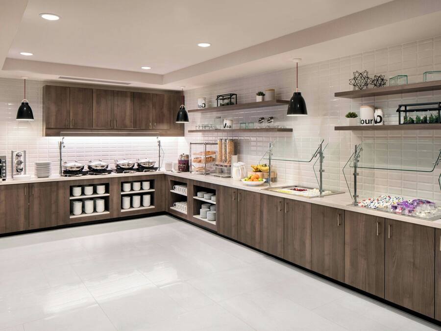 Una cocina moderna con armarios de madera, azulejos blancos y repisas de vidrio.