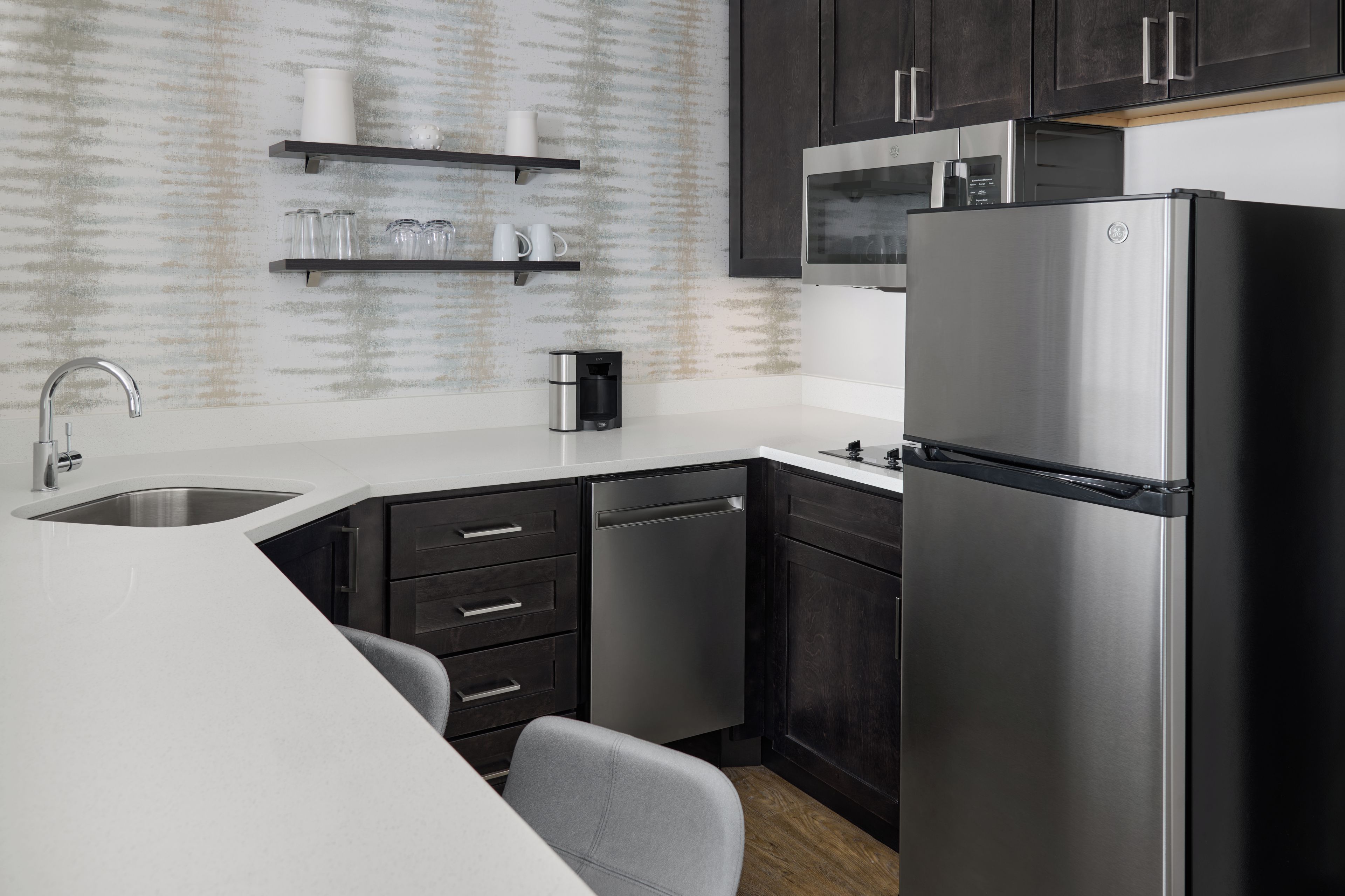 A modern kitchen with a stainless steel refrigerator, a built-in dishwasher, and a microwave.