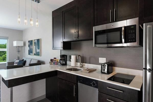 Una cocina moderna con armarios oscuros, electrodomésticos de acero inoxidable, un microondas integrado y una isla grande con pileta.