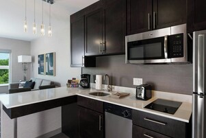 Una cocina moderna con armarios oscuros, electrodomésticos de acero inoxidable, un microondas integrado y una isla grande con pileta.