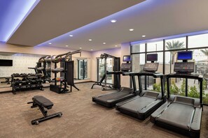 A gym with treadmills, weight machines, and dumbbells.