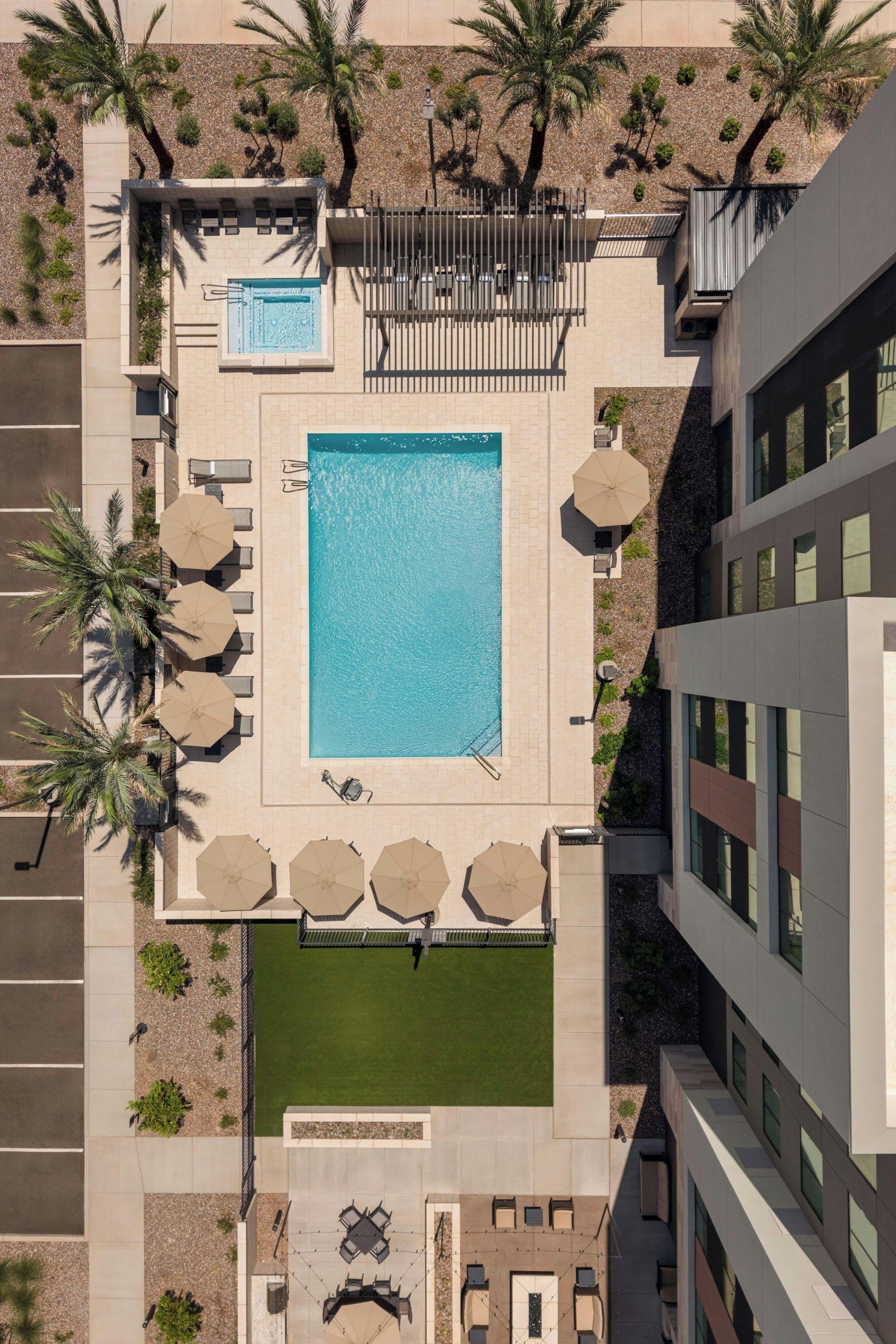 Vista aérea de un hotel con piscina, mobiliario exterior y palmeras.