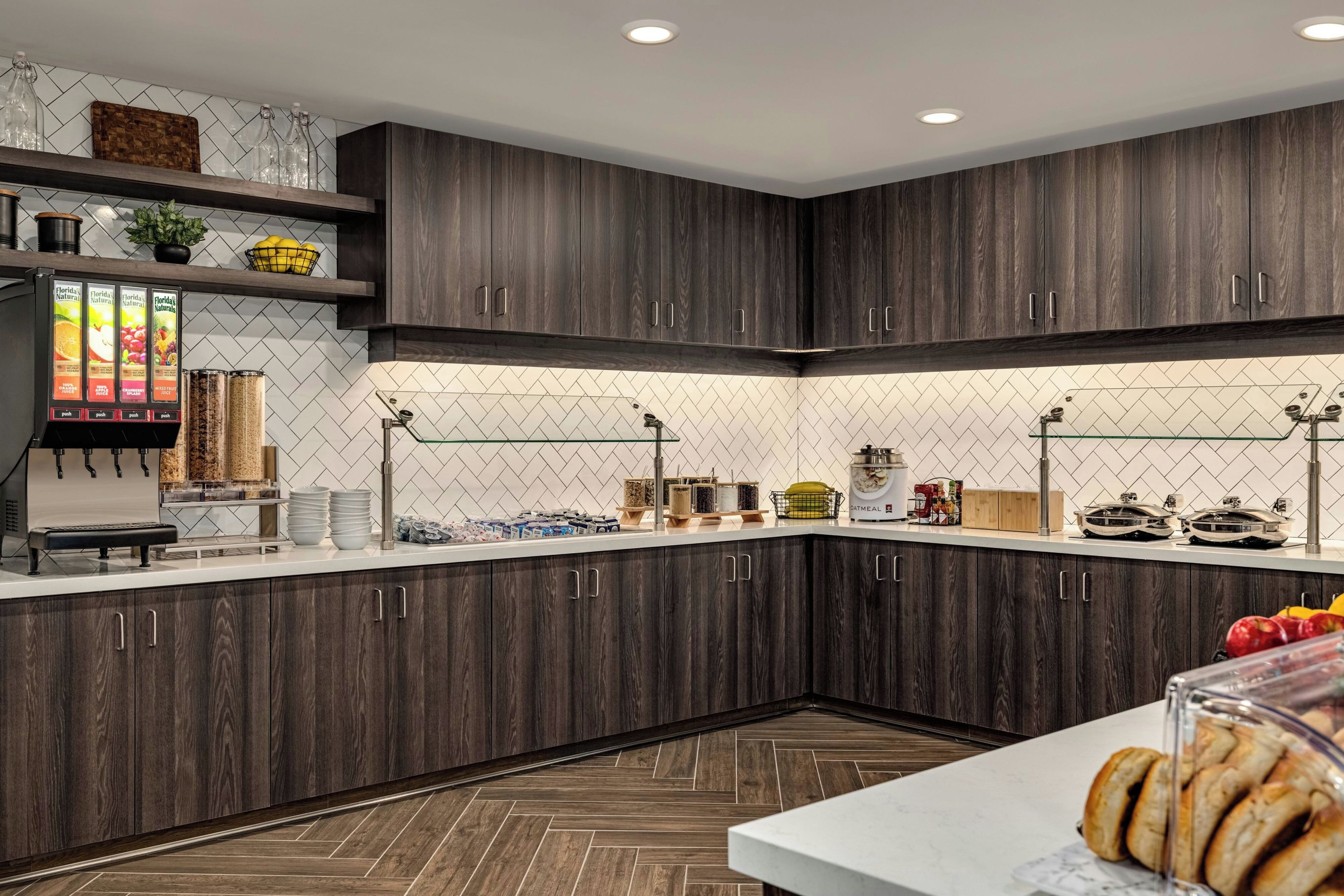 A modern kitchen with dark wood cabinets, a white countertop, and a juice dispenser.