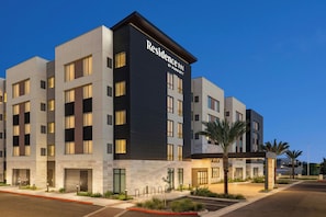 A modern hotel building with a prominent 'Residence Inn by Marriott' sign, multiple floors, and a well-lit entrance area.