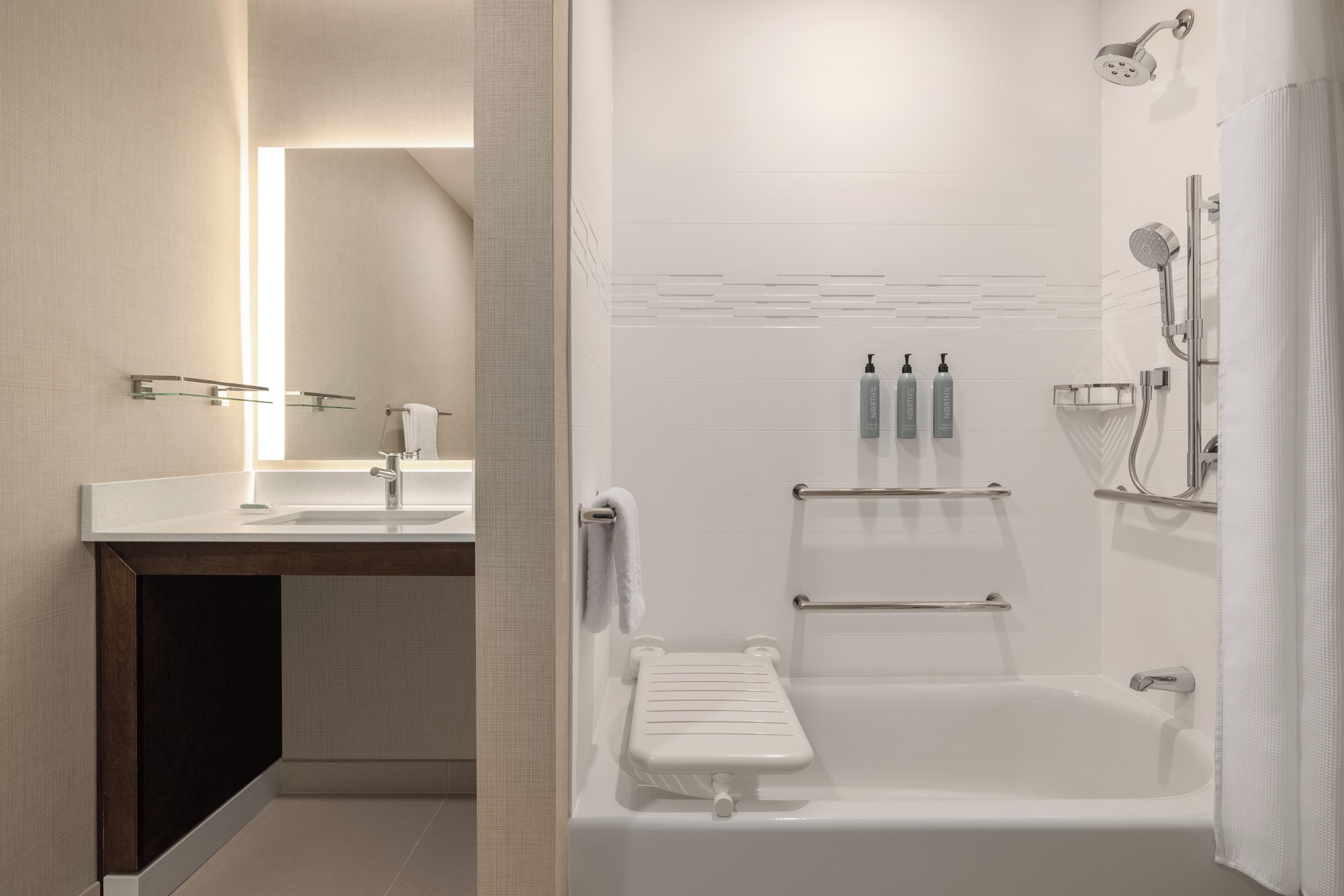 A modern bathroom with a bathtub, shower, and a vanity with a mirror.