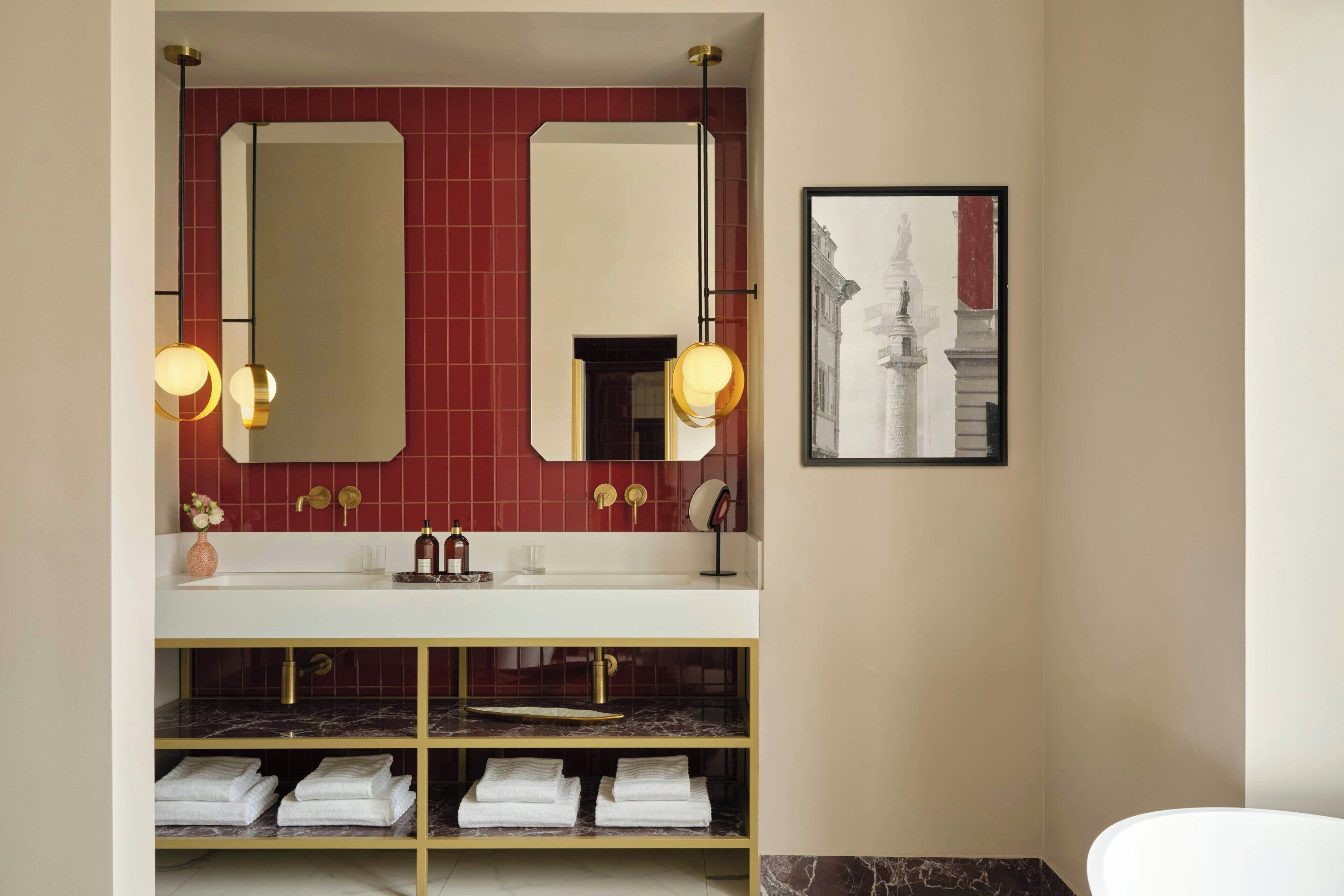 A bathroom with a white sink, two mirrors, and a framed picture on the wall.