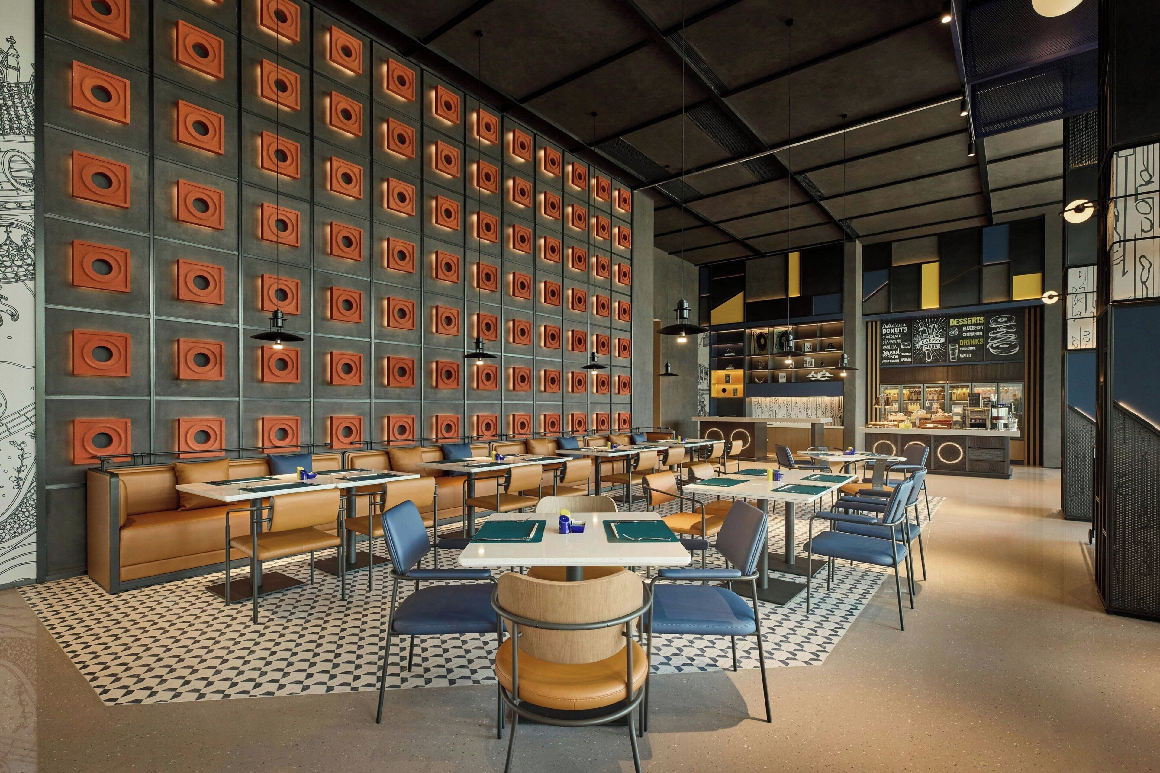 A modern restaurant interior with a patterned wall, booths, tables, and a menu display.