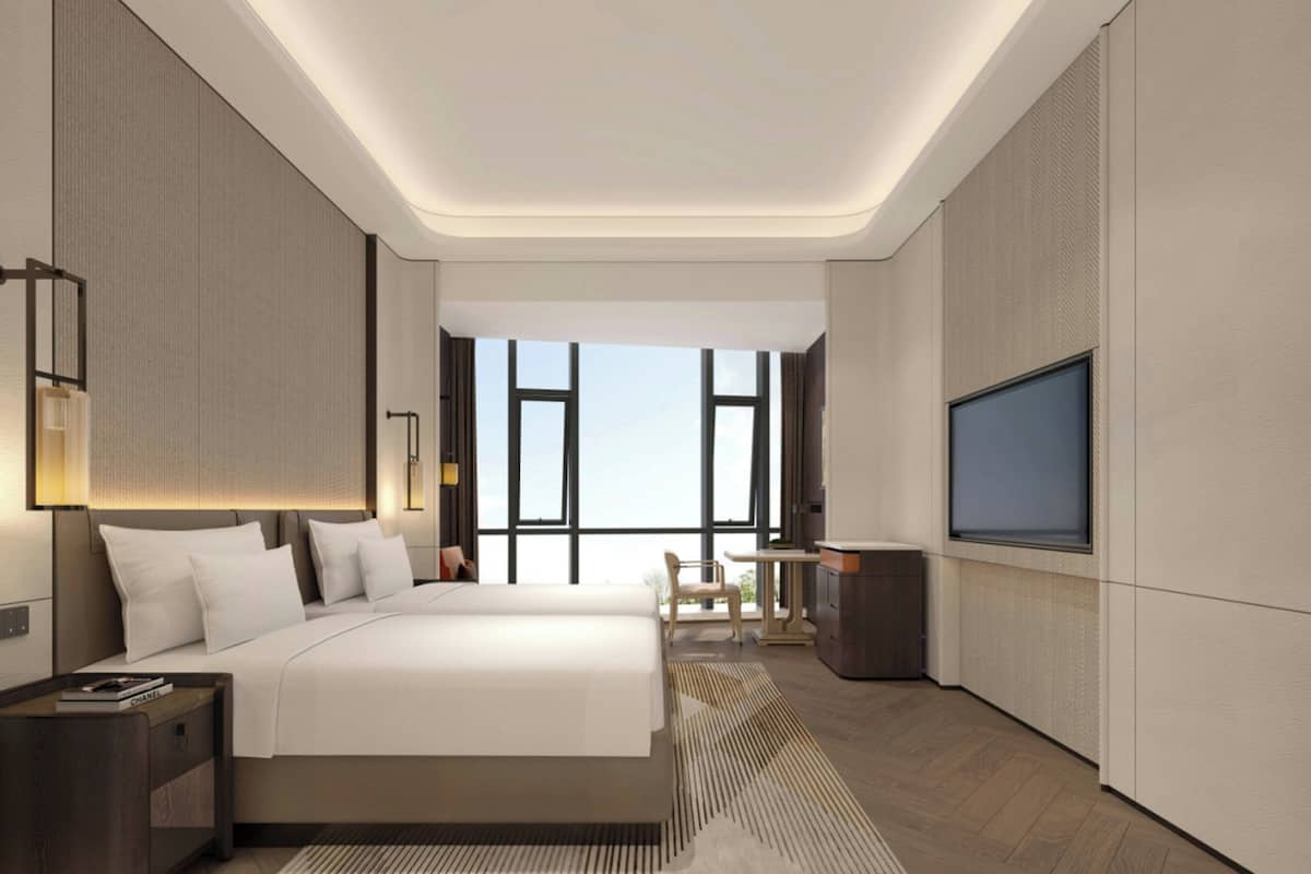Habitación de hotel moderna con una cama grande, un escritorio, un televisor y vistas por las ventanas.