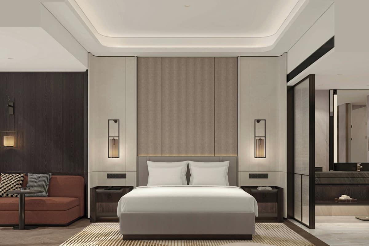Un dormitorio moderno con una cama grande, mesitas de noche, un sillón y un espejo.