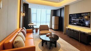 Une chambre d’hôtel moderne équipée d’un canapé, d’une table basse, d’une télévision et d’un coin repas.