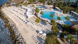 Ein Resort mit Strand, Pool und einem Gebäude mit Dach.