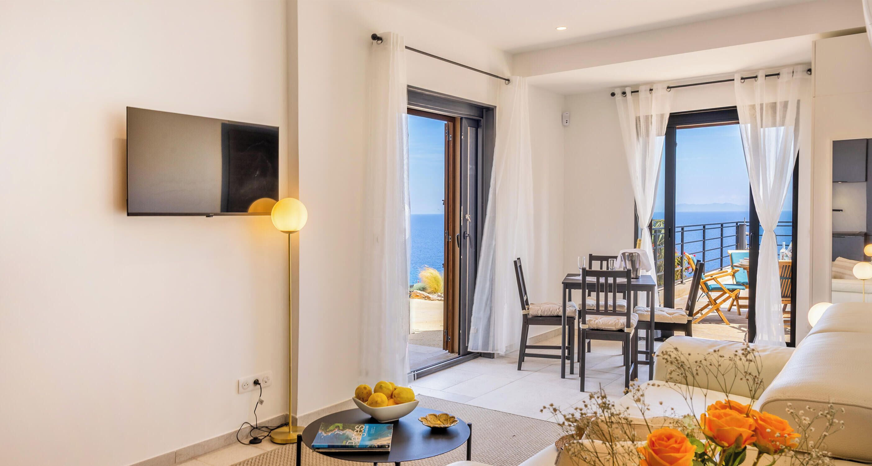 Una sala moderna con un televisor de pantalla plana, un comedor con sillas, una mesa y un balcón con vistas.