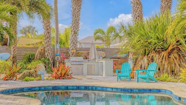 Un jardin avec une piscine, un barbecue et un espace salon extérieur.